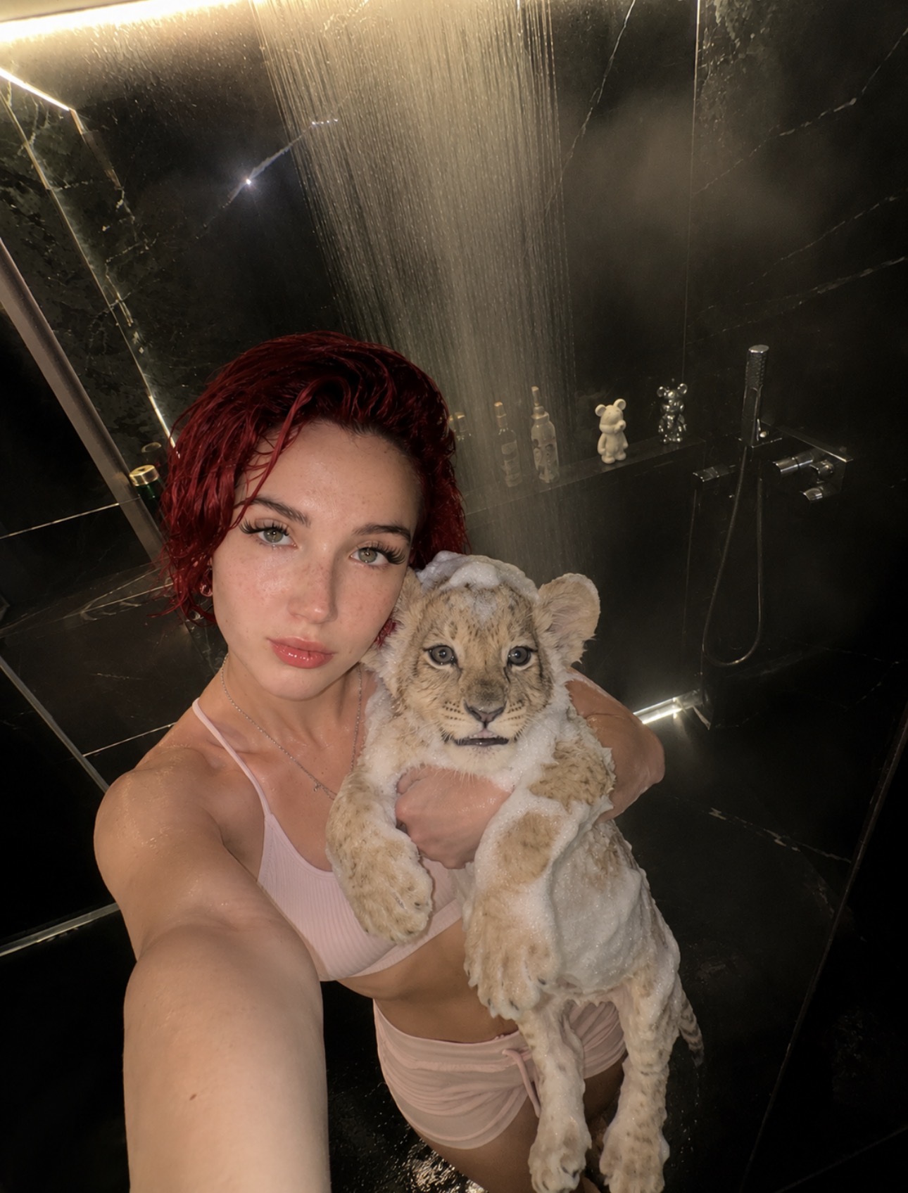 Alice Kwong holding a lion cub in a softly lit shower