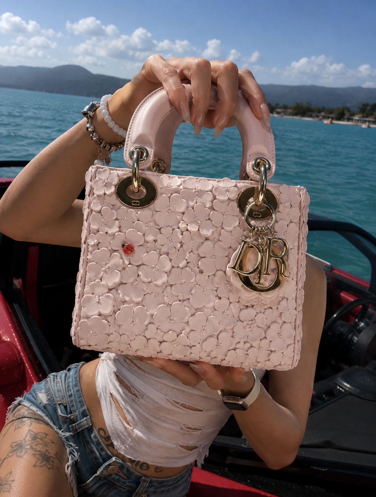 Pink designer bag close-up by blue water